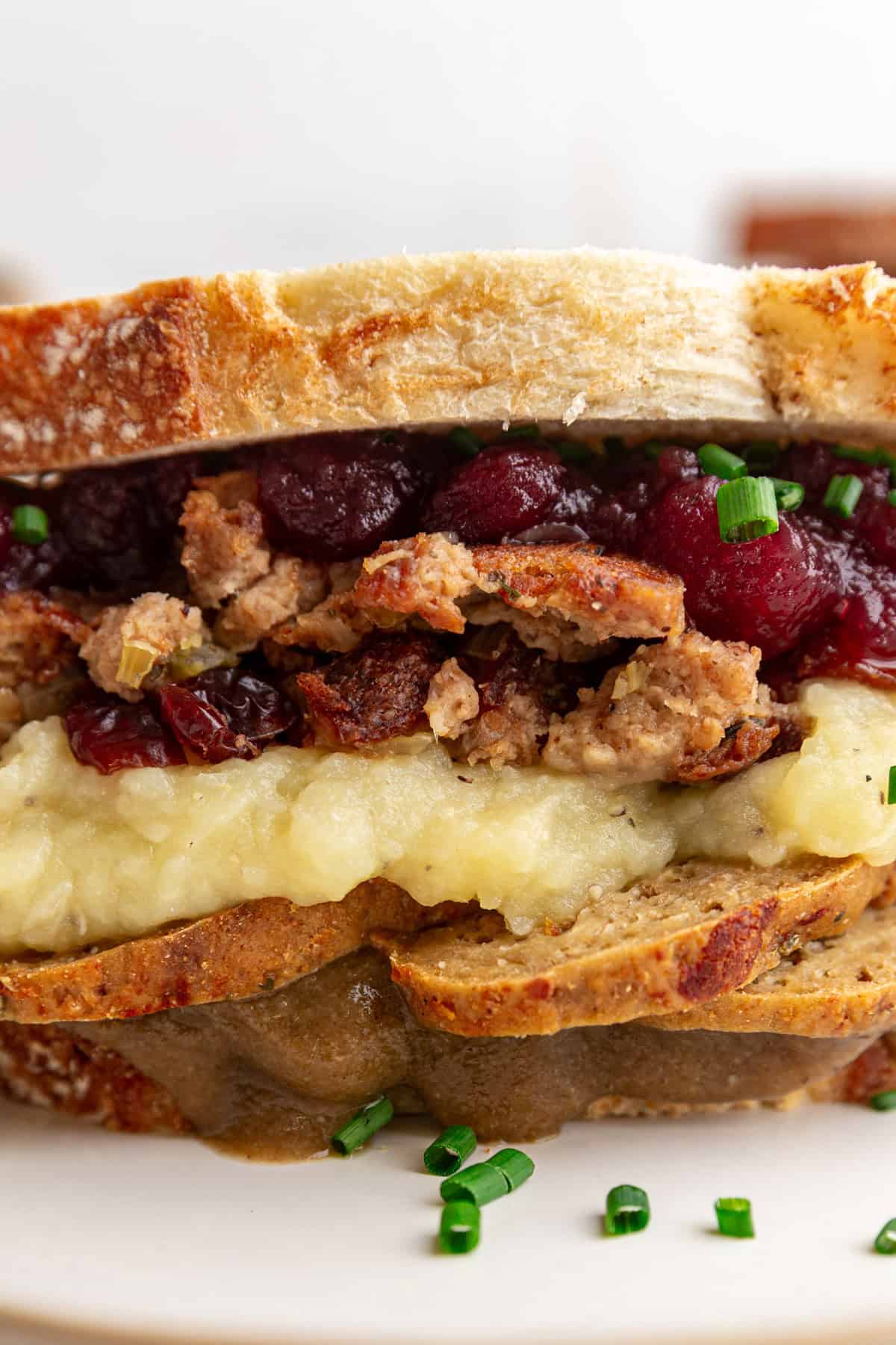 A Vegan Thanksgiving Leftovers Sandwich, loaded with stuffing, mashed potatoes, and cranberry sauce.