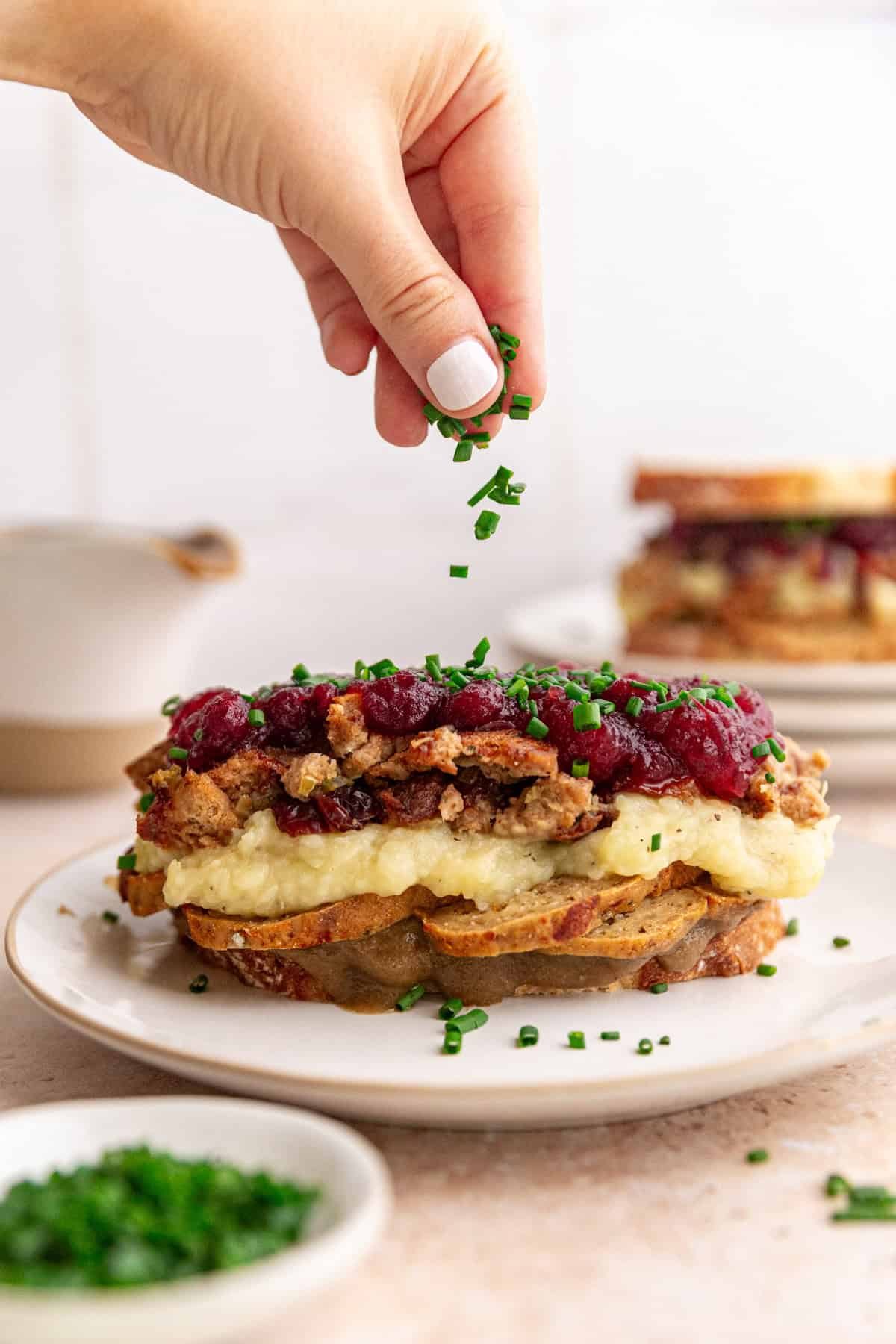 Sprinkling chives onto a vegan thanksgiving leftovers sandwich.