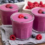 A Blueberry Raspberry Smoothie, garnished with a fresh raspberry and blueberry.