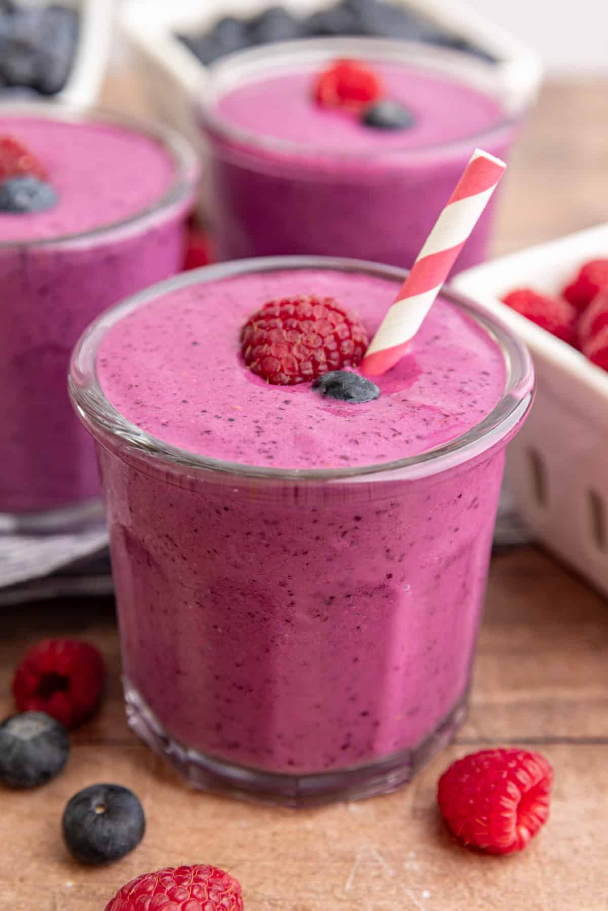 A Blueberry Raspberry Smoothie, with a straw, ready to drink.