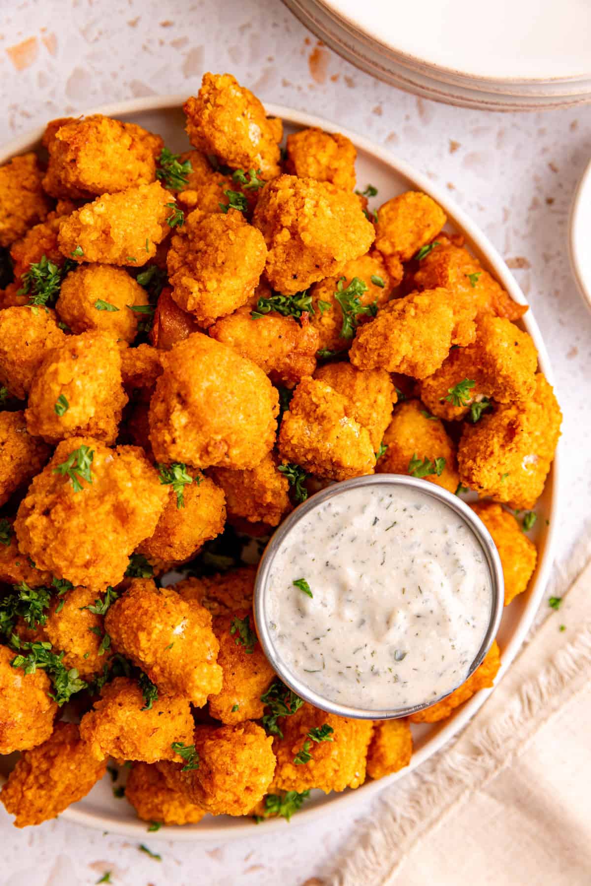 A plate of buffalo tofu poppers with a container of vegan ranch.