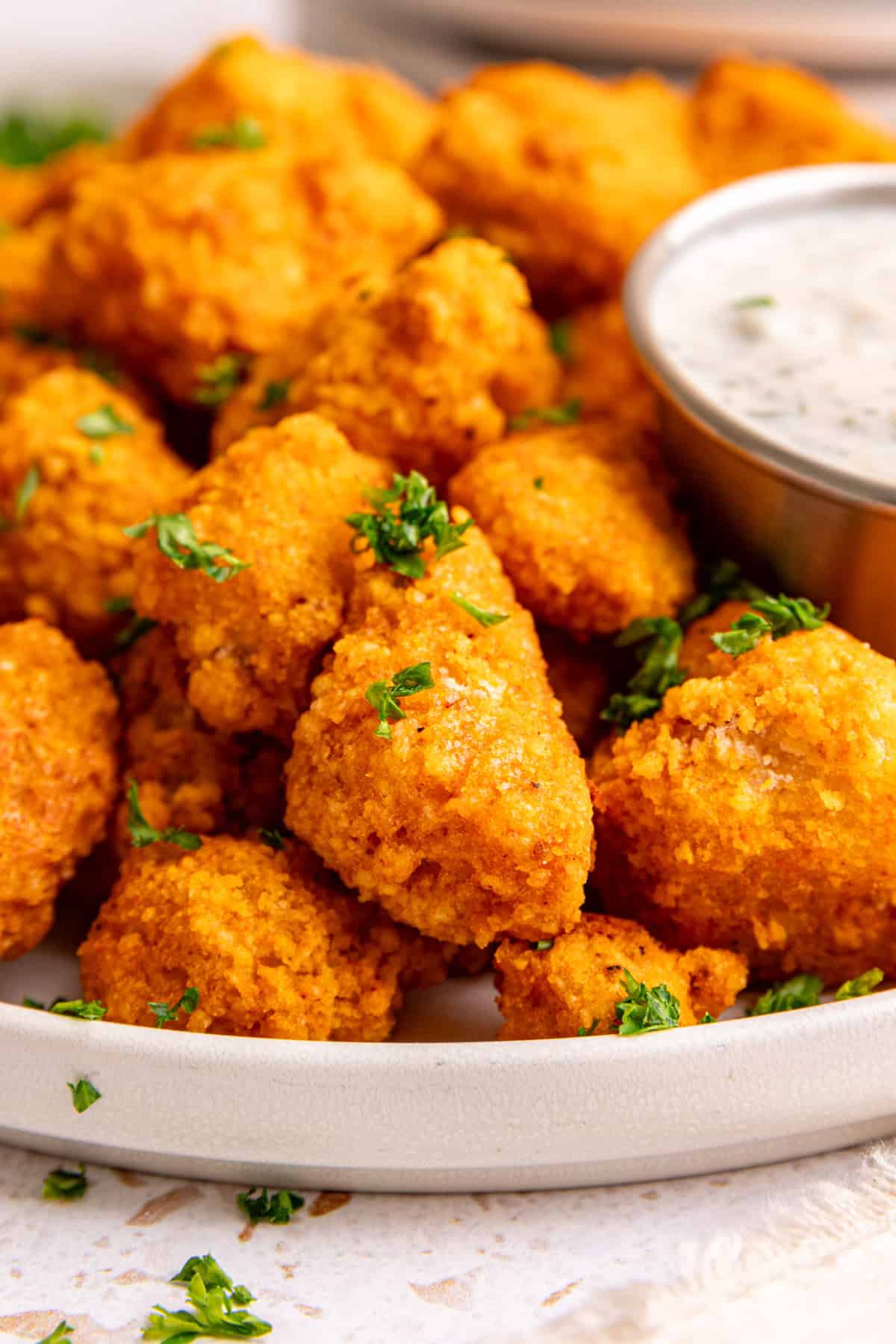 A close up view of a plate of buffalo tofu poppers to show the bite-size and crispy texture.
