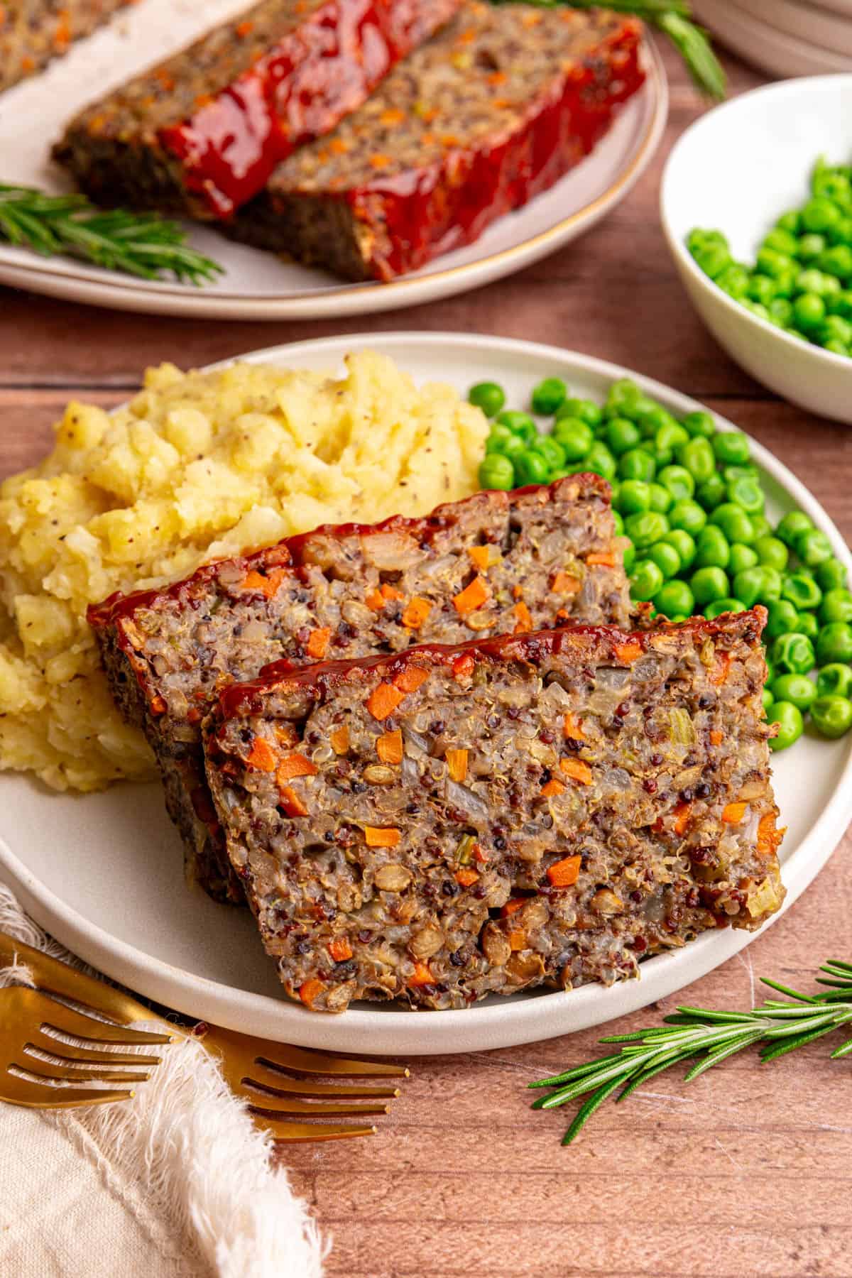 A plate of two slices of lentil quinoa loaf, mashed potatoes, and peas.