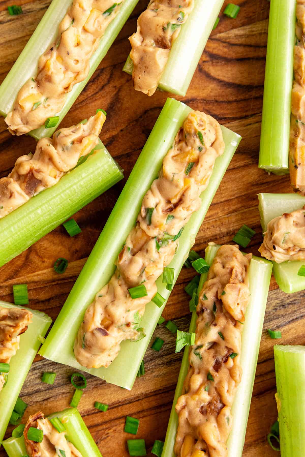A close up view of a section of vegan stuffed celery, garnished with fresh chives.