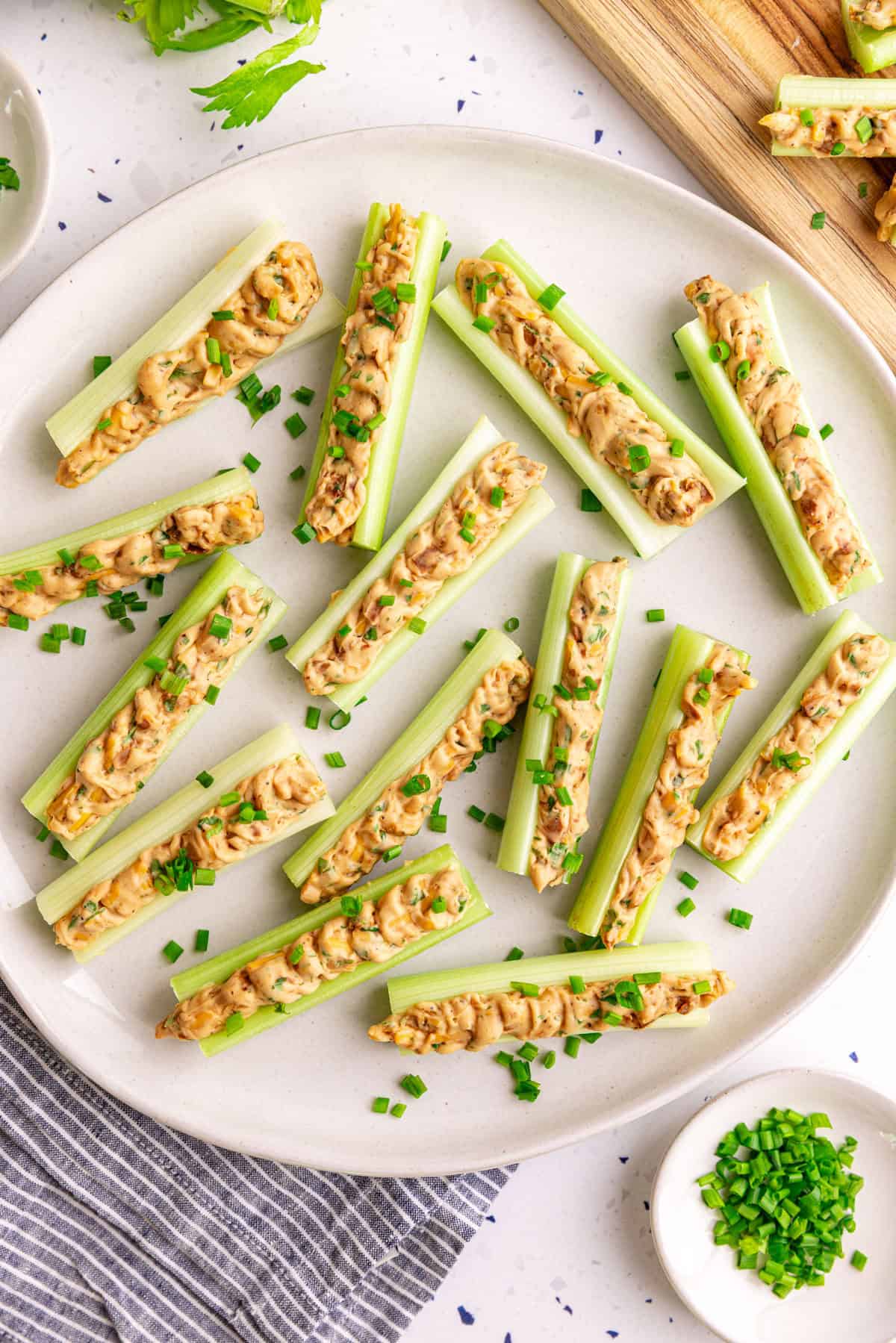 A plate of vegan stuffed celery garnished with chives.