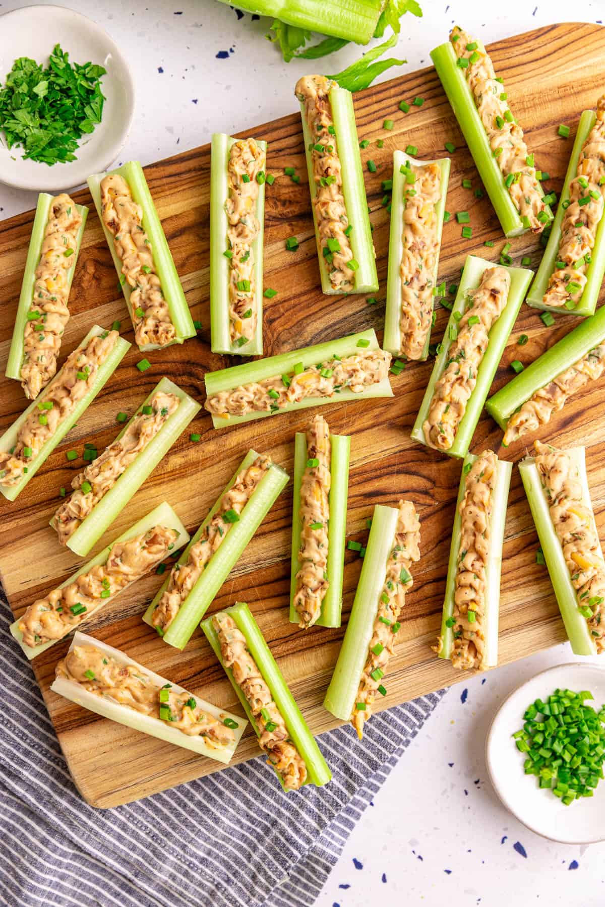 A board with vegan stuffed celery garnished with chives.