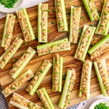 A board with vegan stuffed celery garnished with chives.