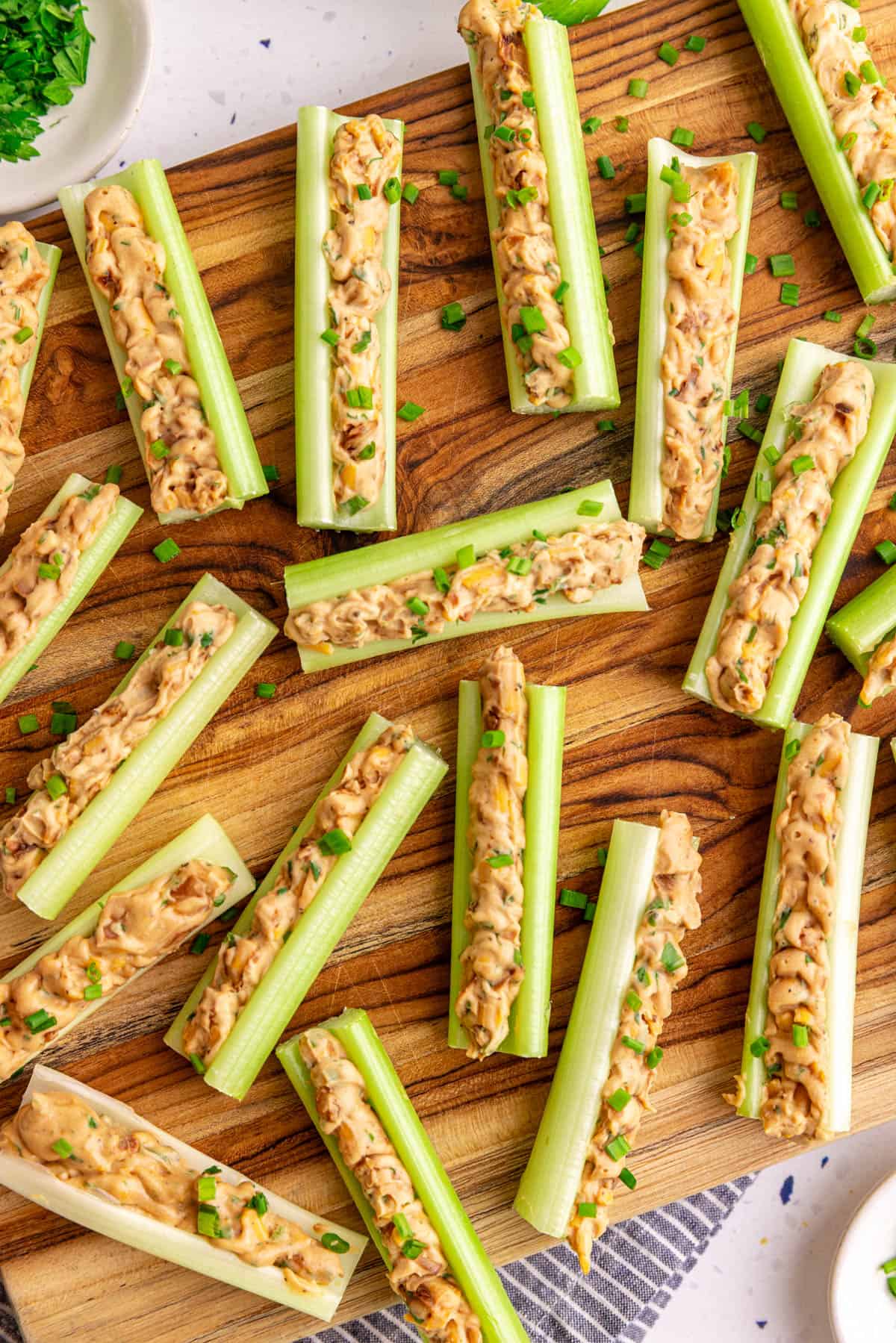 A board with vegan stuffed celery garnished with chives.
