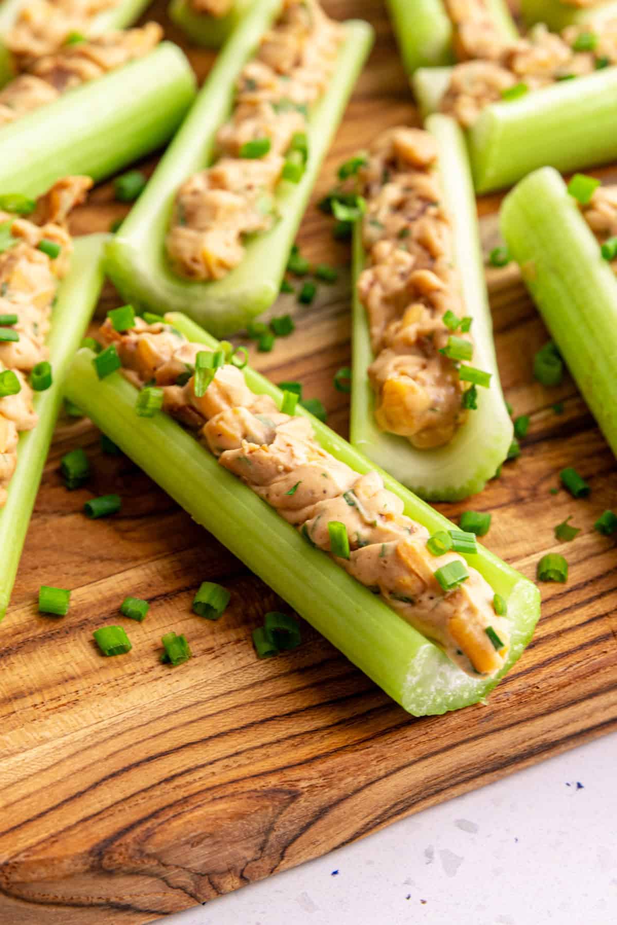 A close up view of a section of vegan stuffed celery, garnished with fresh chives.
