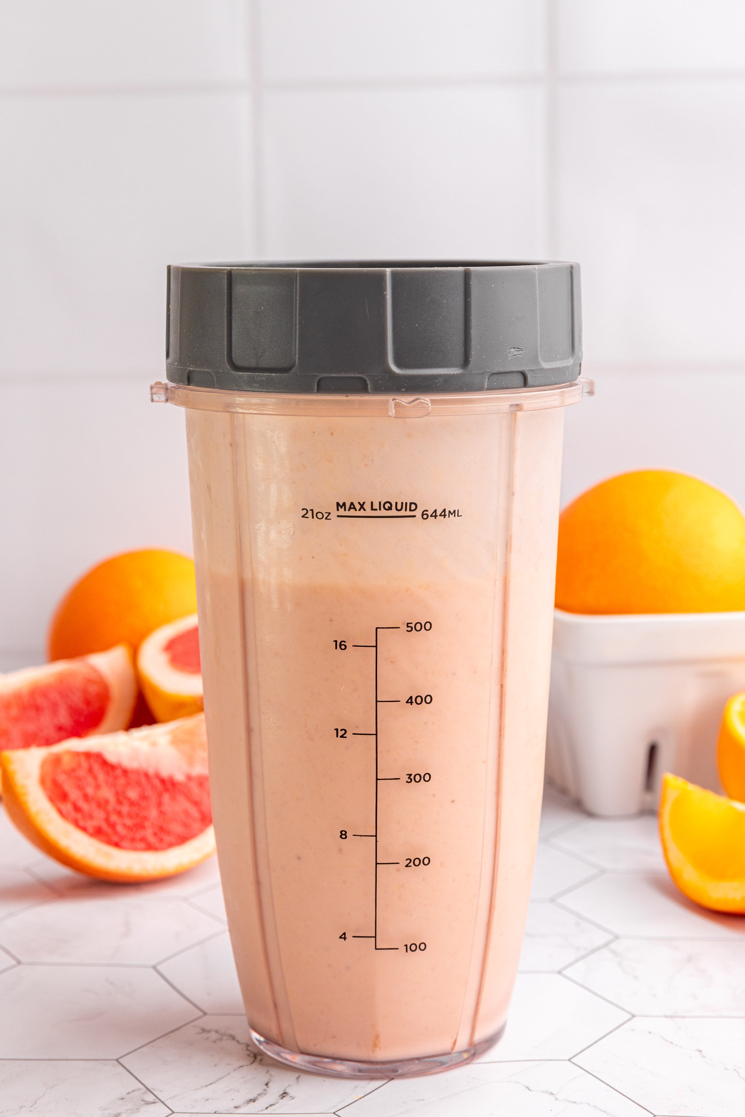 A blender cup of blended citrus smoothie.