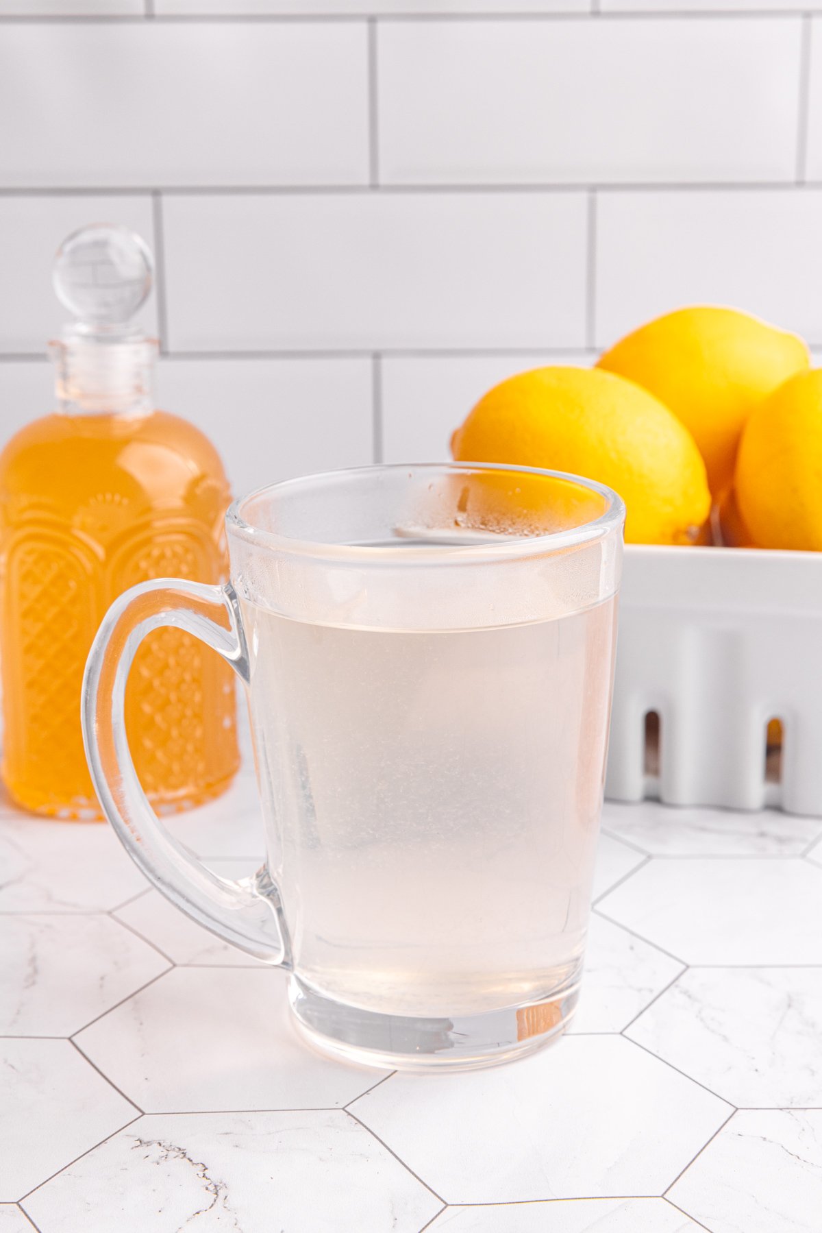 A glass of hot lemon ginger tea on a countertop.