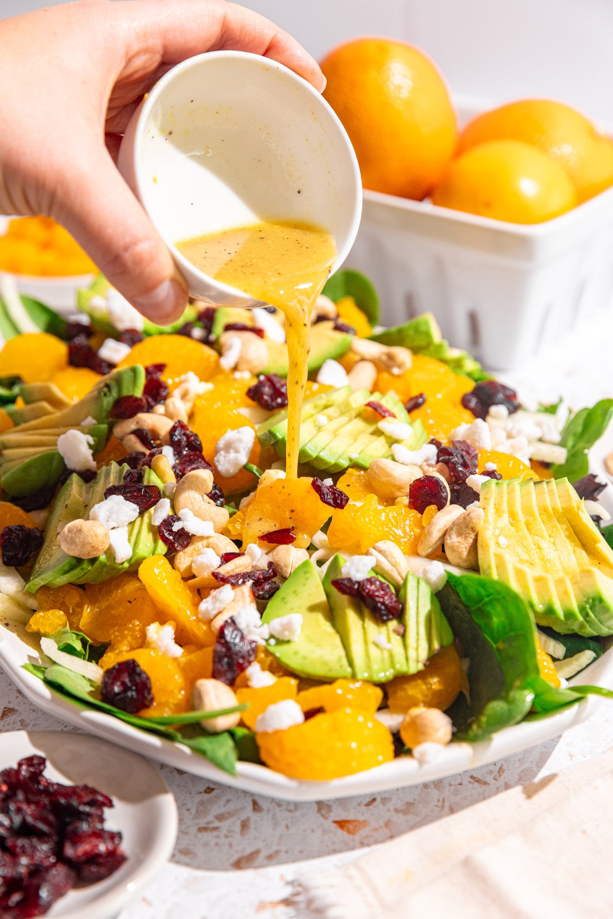 Dressing being poured onto a platter of mandarin orange salad.