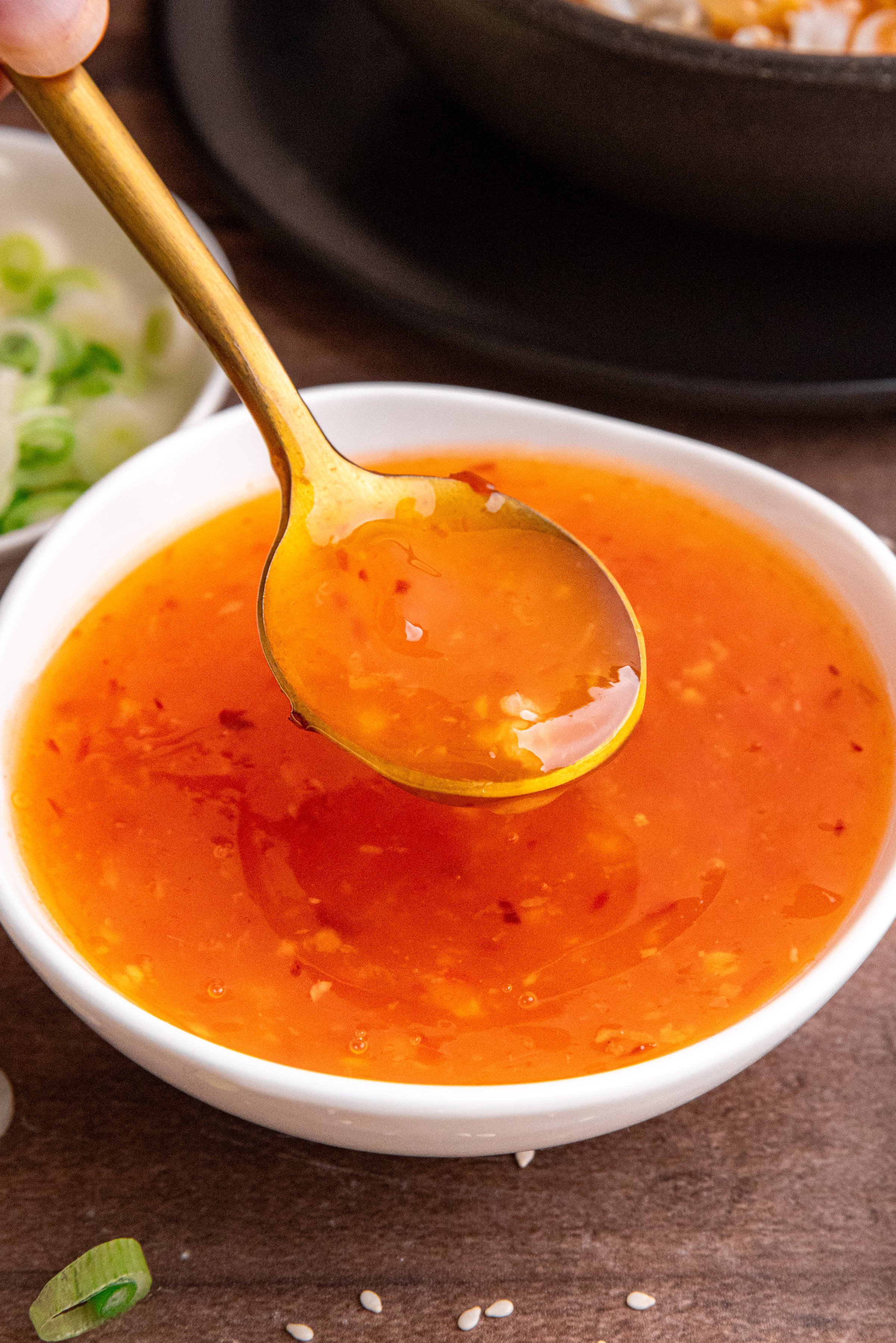 A spoon scooping a spoonful of sweet chili sauce.