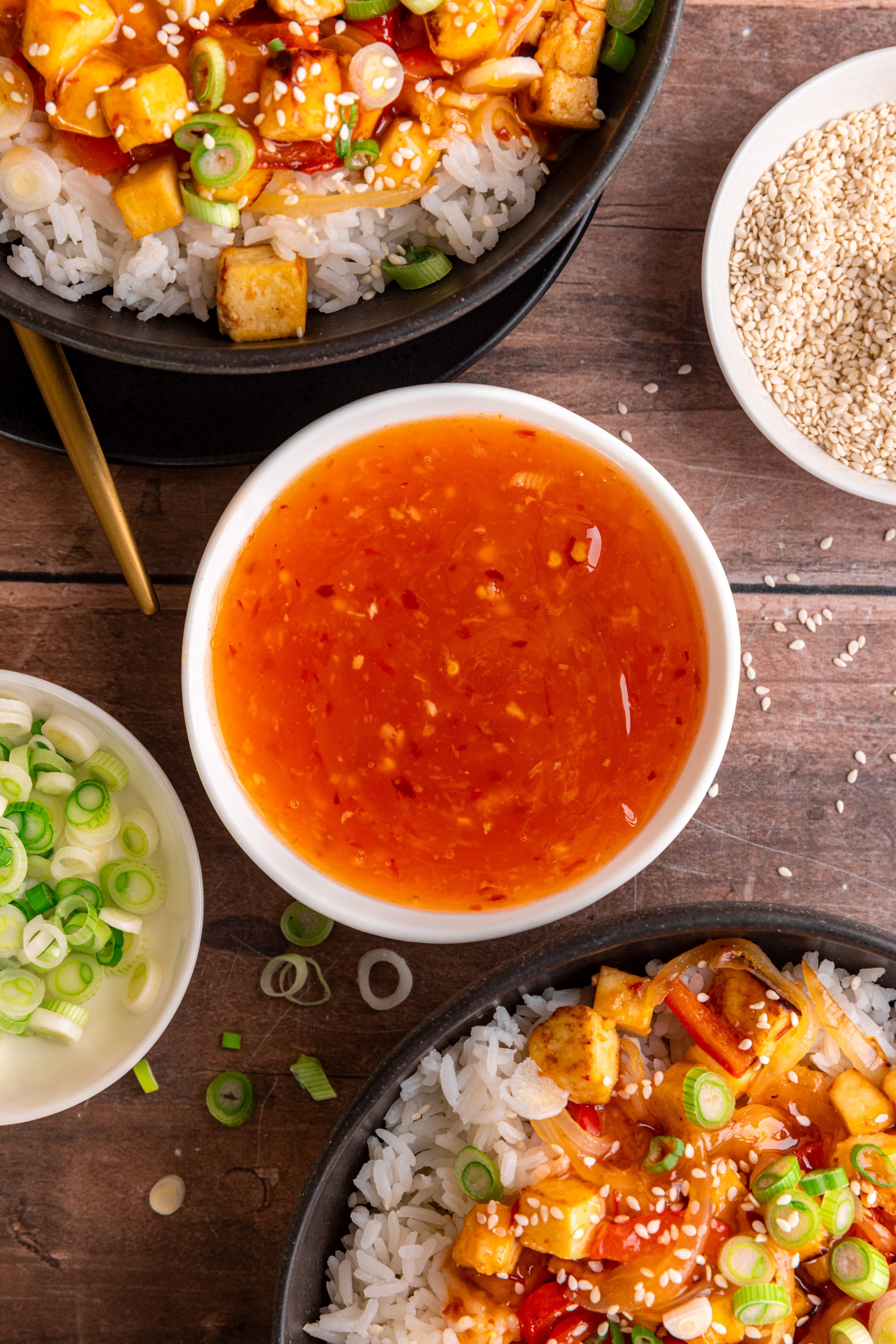 A bowl of sweet chili sauce, next to a bowl of sweet chili tofu.