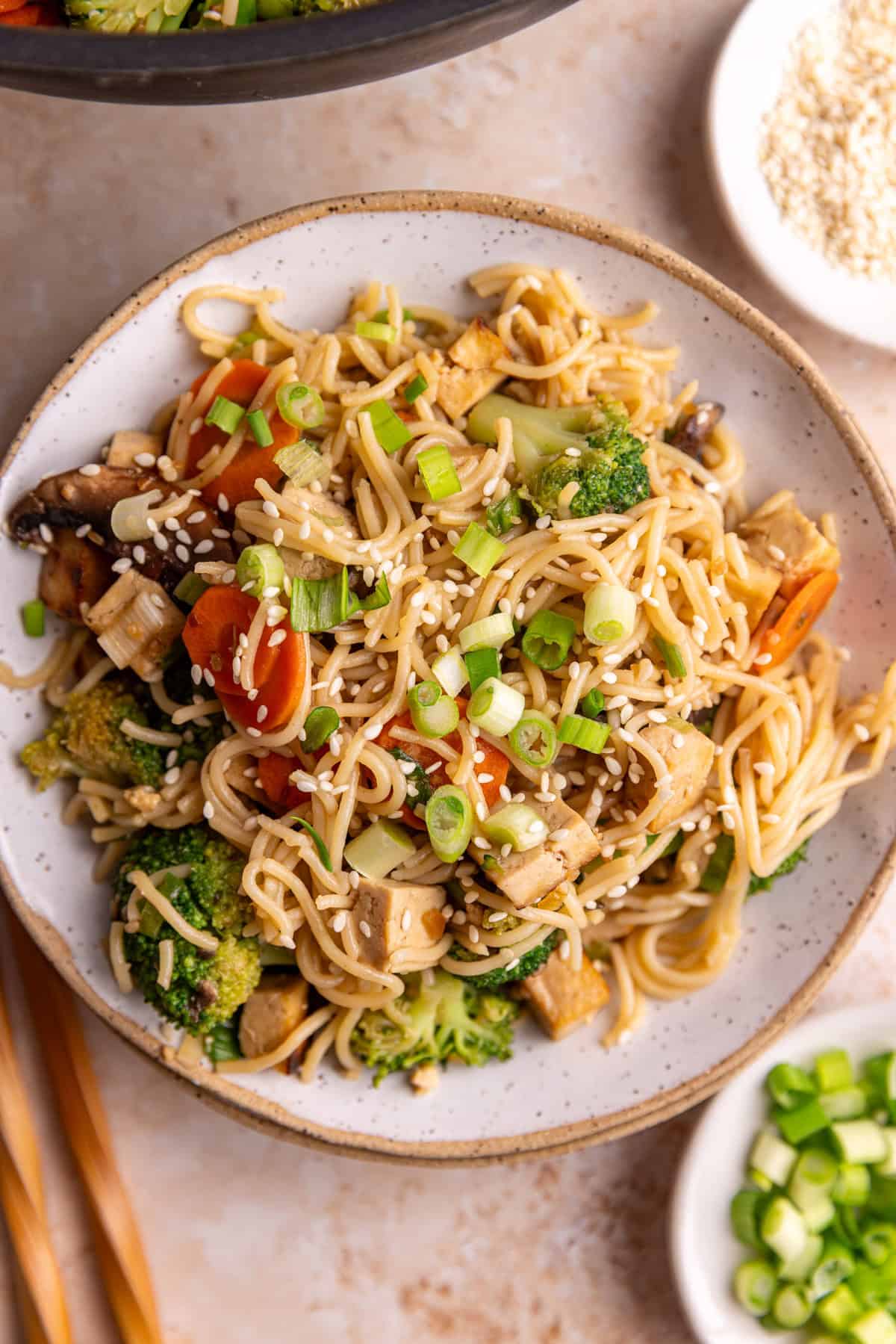 A teriyaki noodle bowl, with chopsticks, ready to eat.