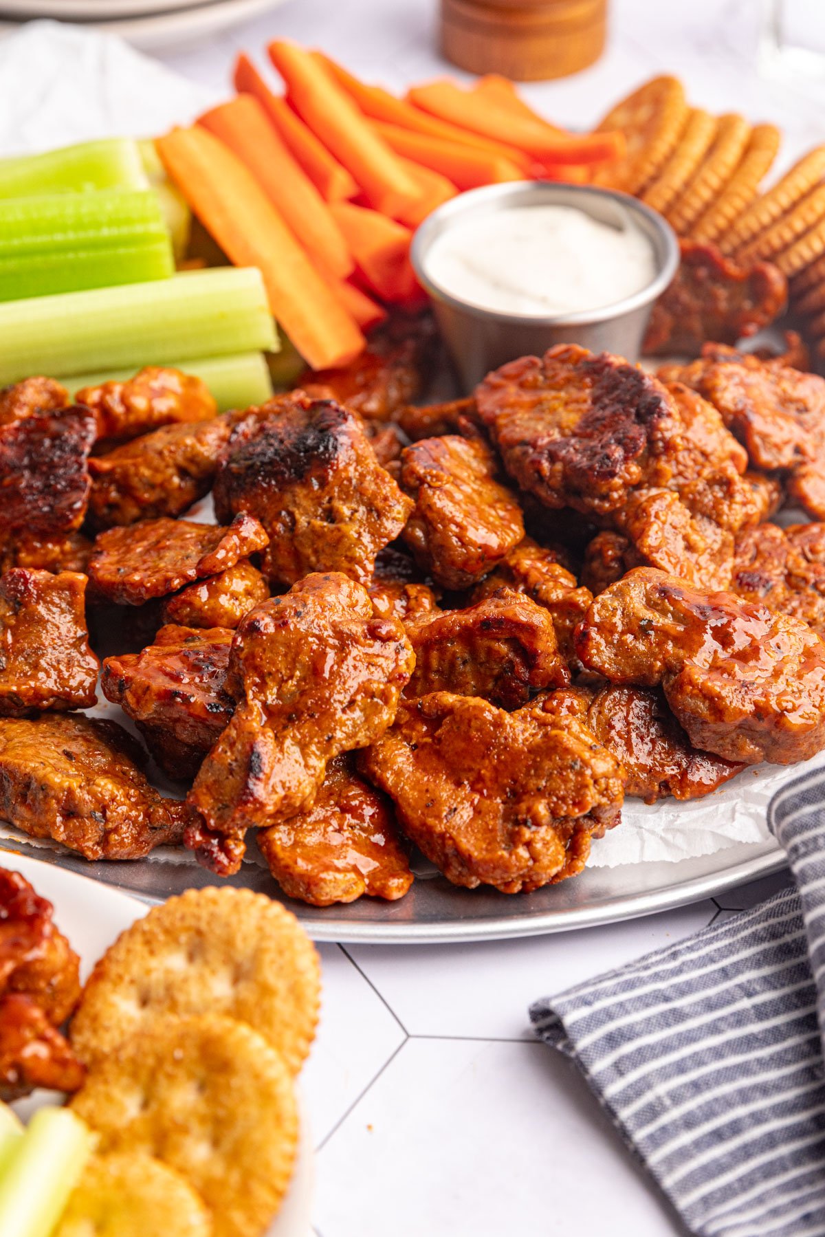 A tray of vegan buffalo seitan wings, with carrots and celery.