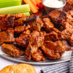 A tray of vegan chicken wings, with carrots and celery.