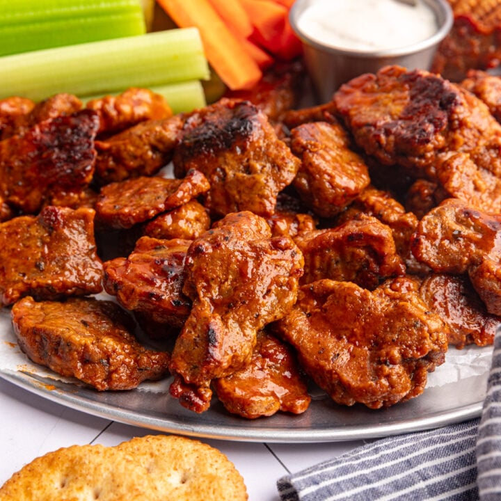 A tray of vegan chicken wings, with carrots and celery.