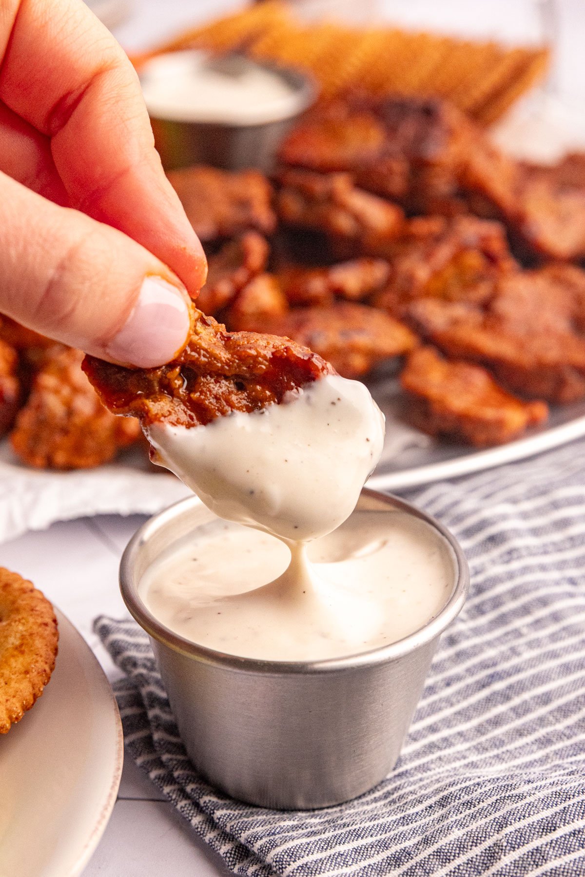 A vegan seitan buffalo wing being dipped into ranch.