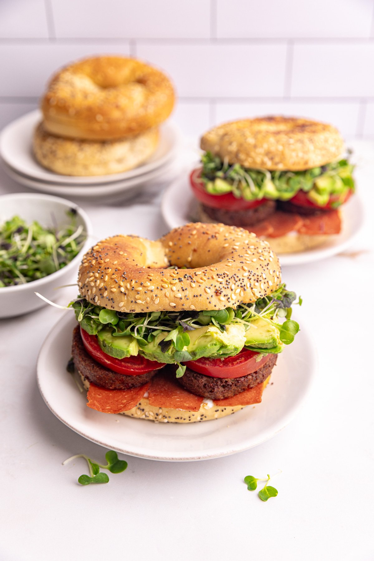 A vegan bagel breakfast sandwich, on a plate, ready to eat.