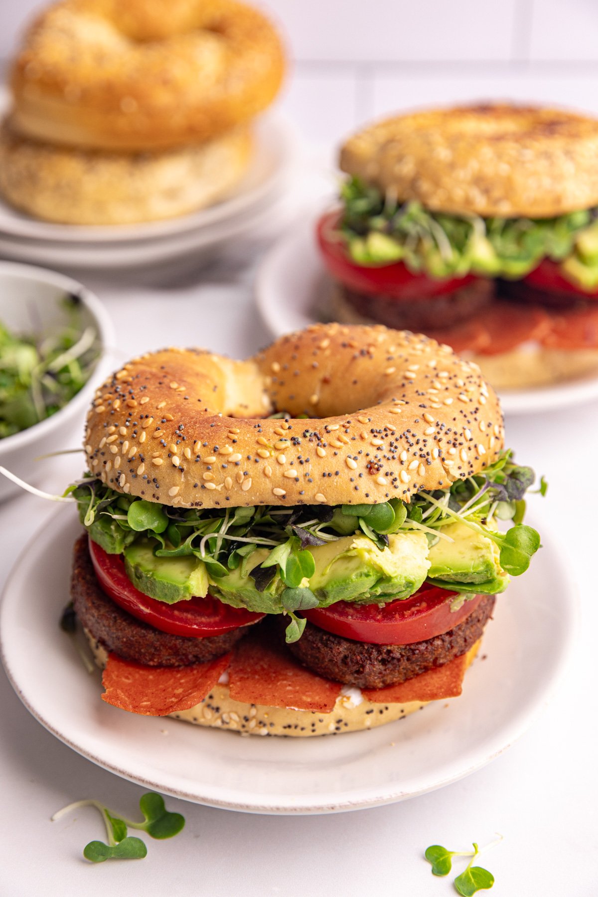 A vegan bagel breakfast sandwich, on a plate, ready to eat.