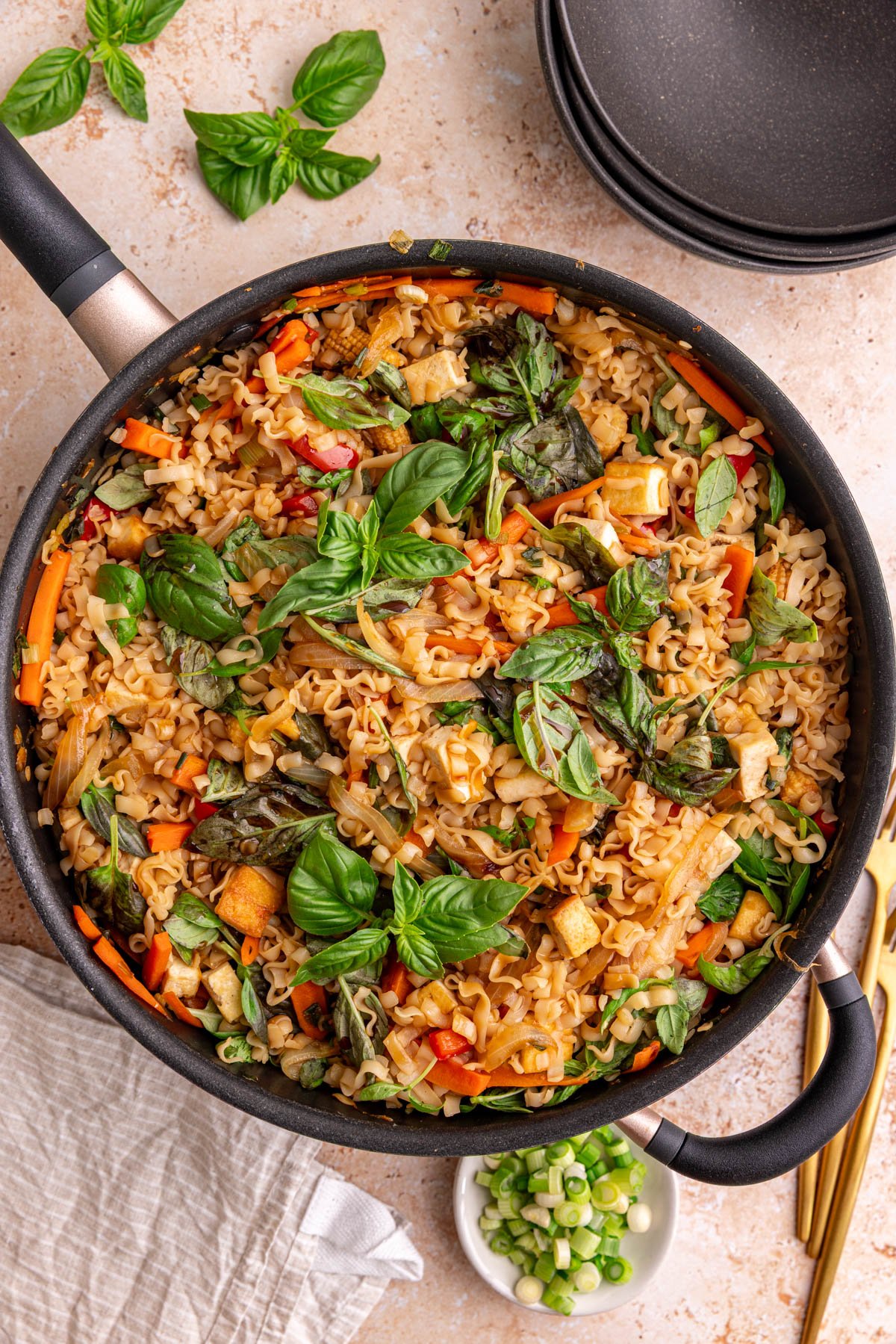 A pan of freshly cooked vegan drunken noodles, garnished with basil.