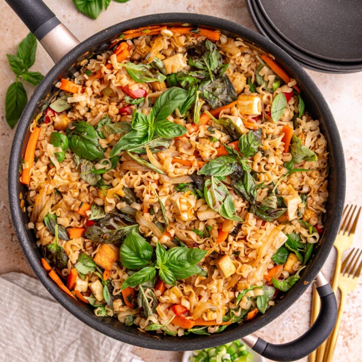 A pan of freshly cooked vegan drunken noodles, garnished with basil.