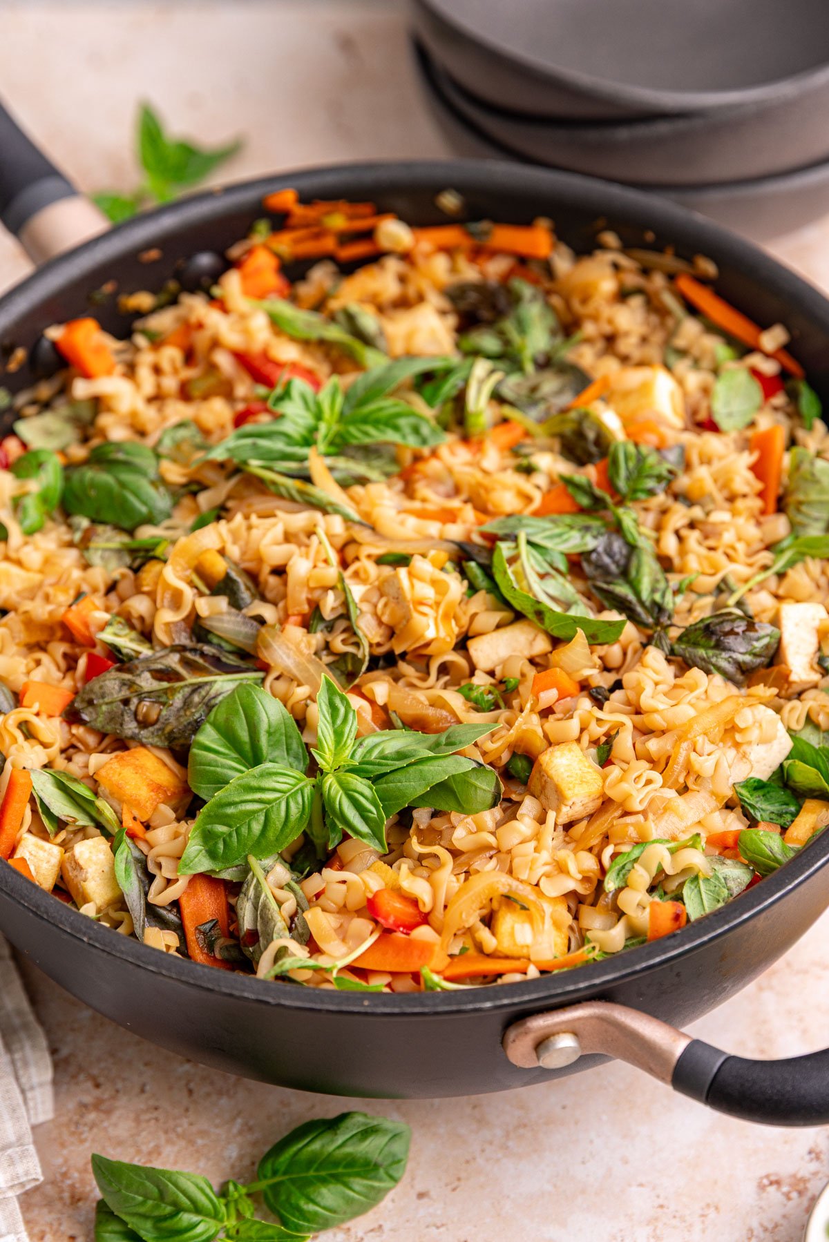 A pan of freshly cooked vegan drunken noodles, garnished with basil.