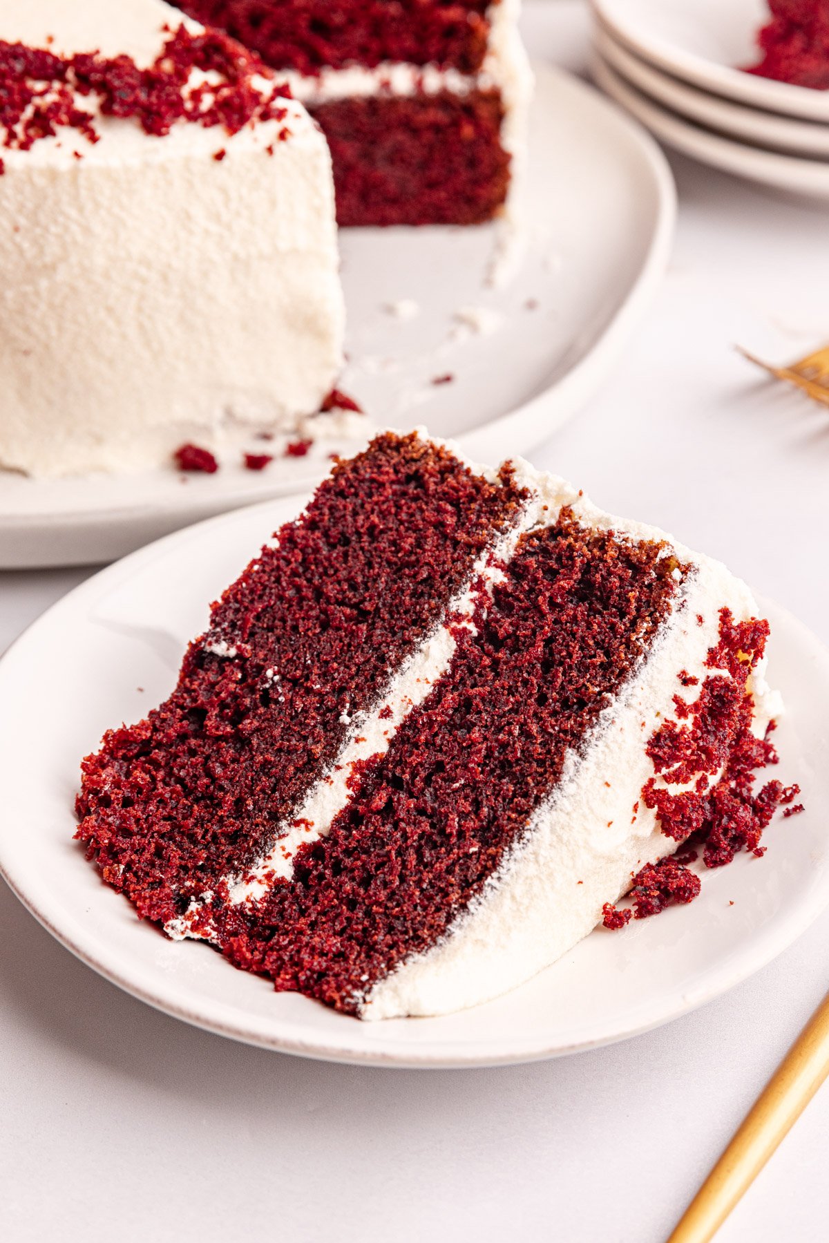 A slice of vegan red velvet cake laying on its side on a plate.
