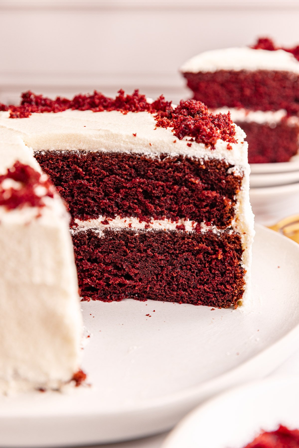 A platter of vegan red velvet cake with several slices cut from it.