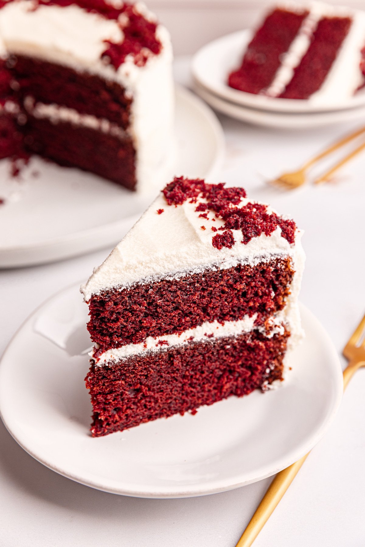 A slice of vegan red velvet cake standing on a plate.