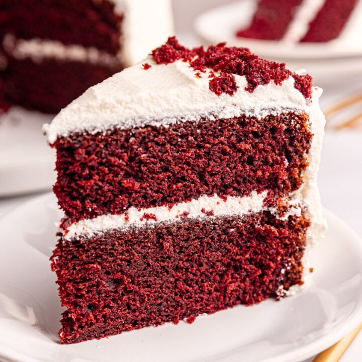 A slice of vegan red velvet cake standing on a plate.