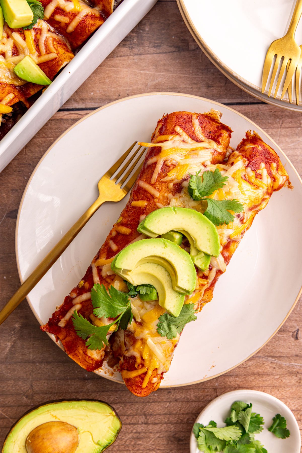 Two enchiladas on a plate, with a fork, ready to eat.