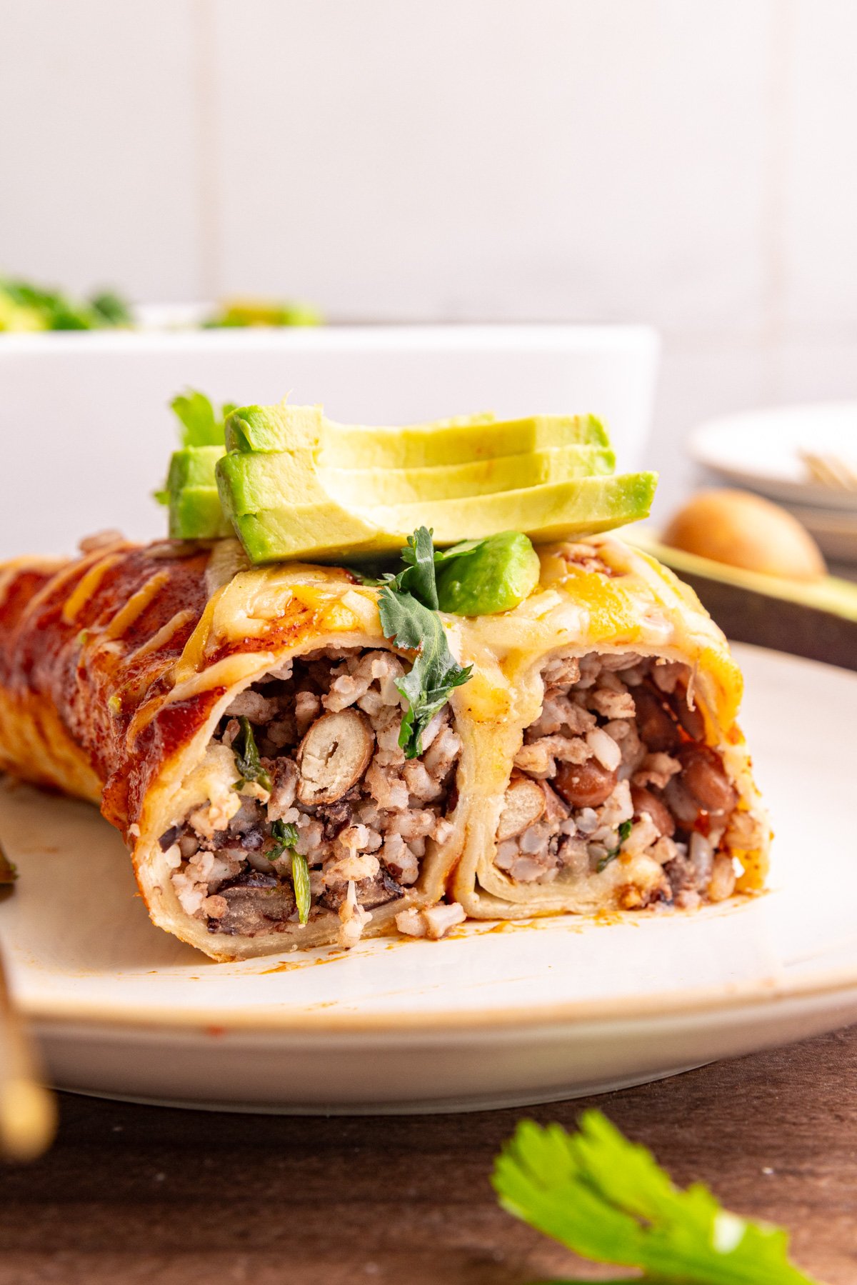 Two enchiladas on a plate, sliced to see the rice and bean filling.