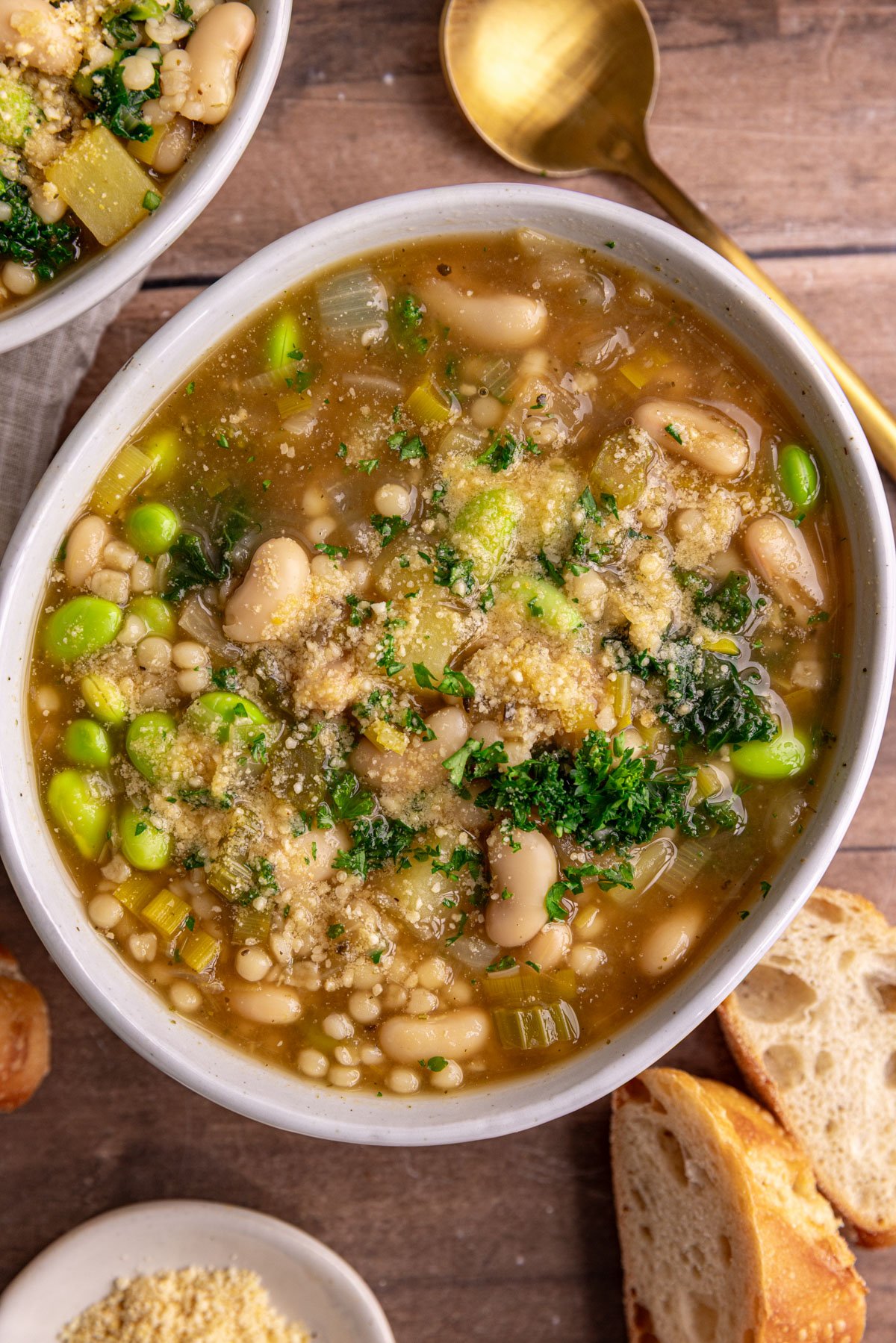 A bowl of white minestrone soup garnished with vegan parmesan.