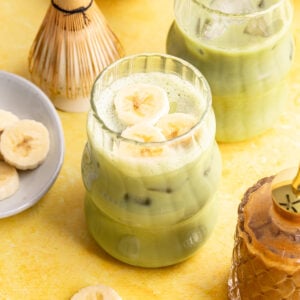 A banana cream matcha latte, with a few banana slices on top.