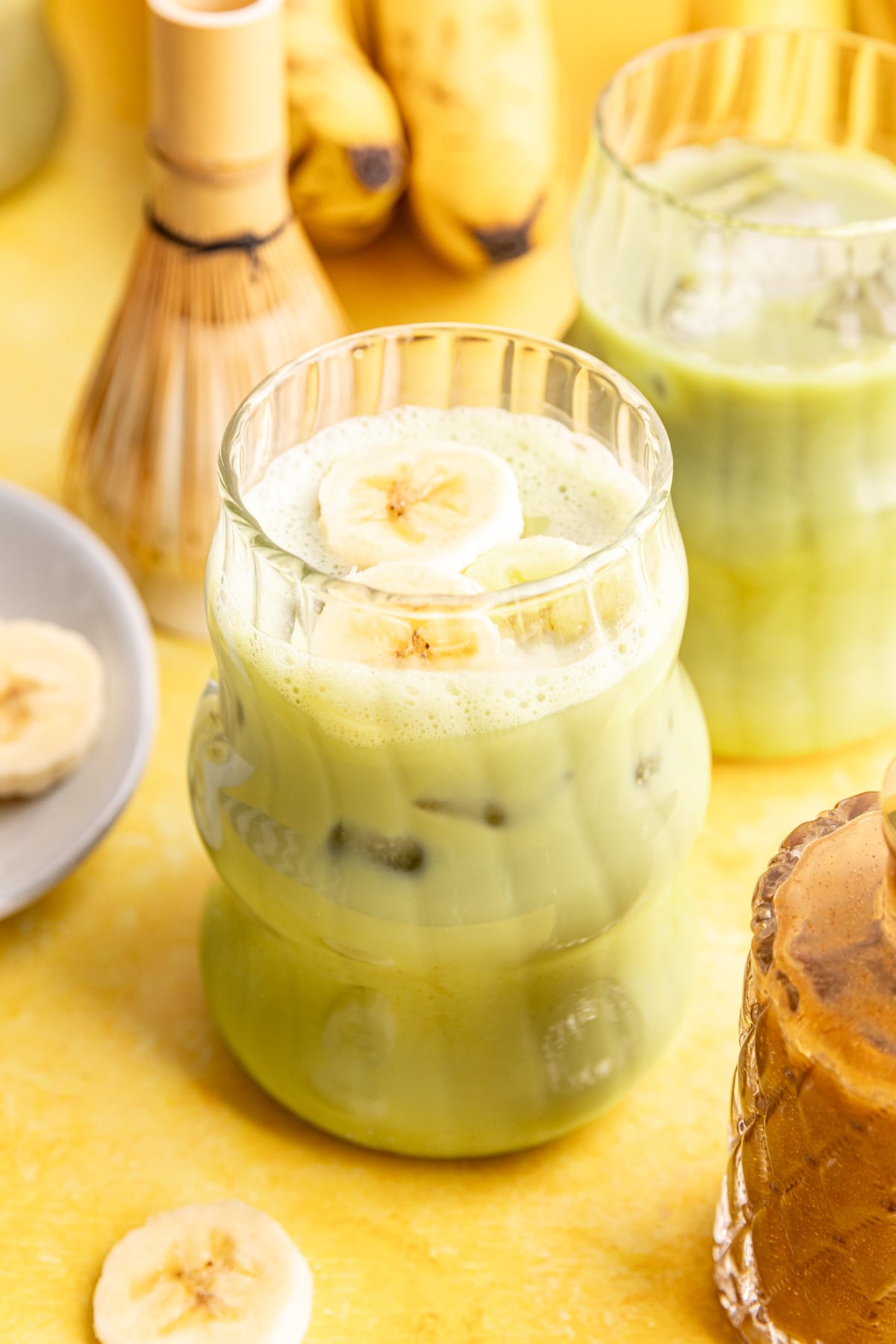 A banana cream matcha latte, with a few banana slices on top.