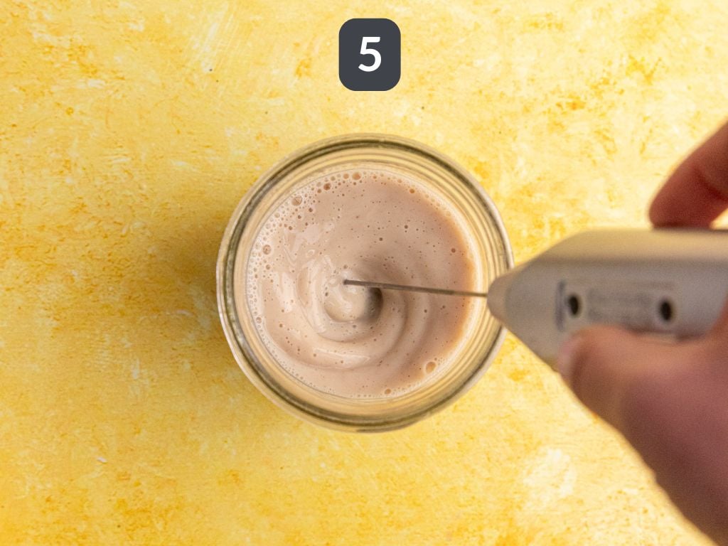 Banana cream matcha latte step 5 - whisk the milk and banana syrup.