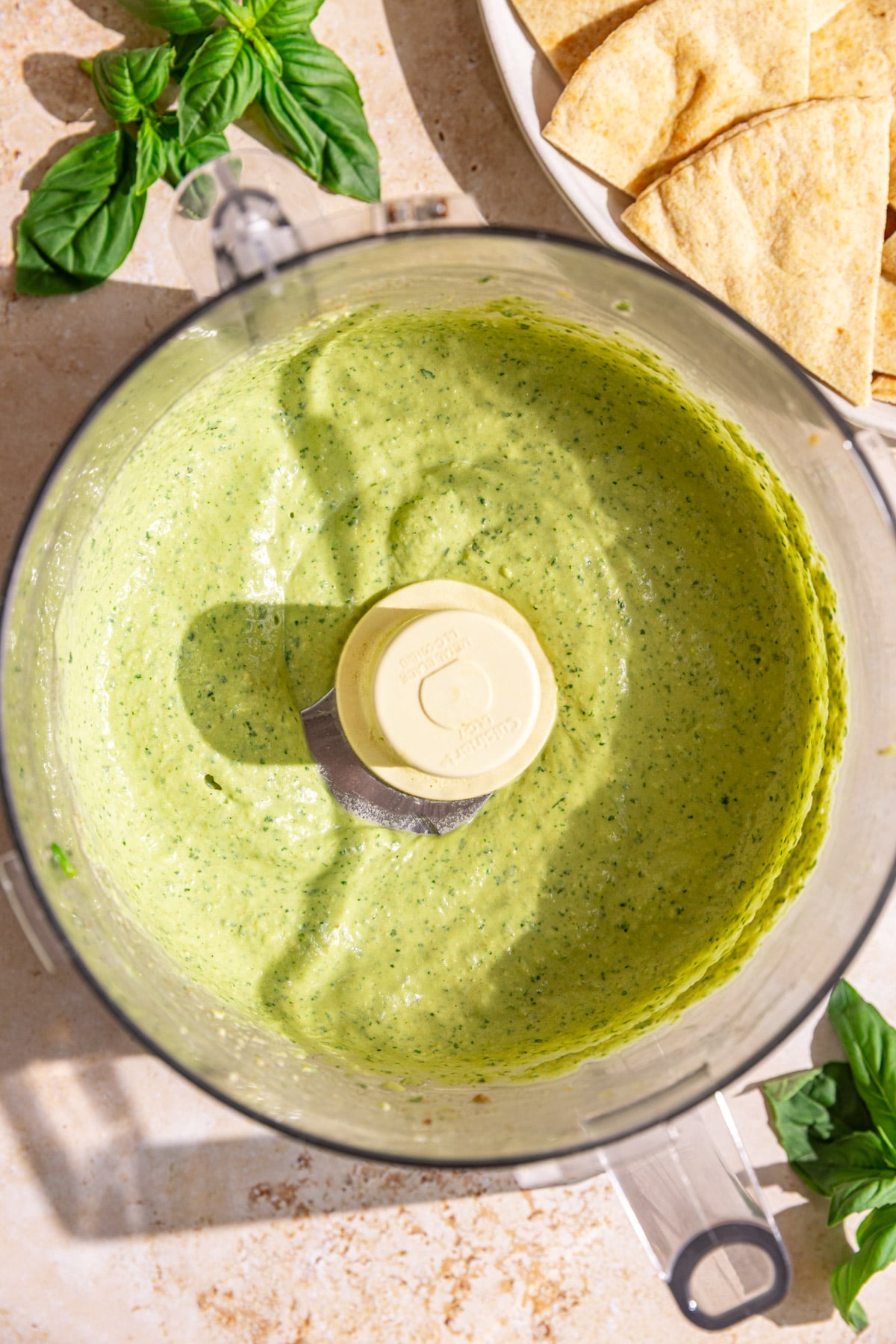 A food processor bowl with freshly made basil hummus.