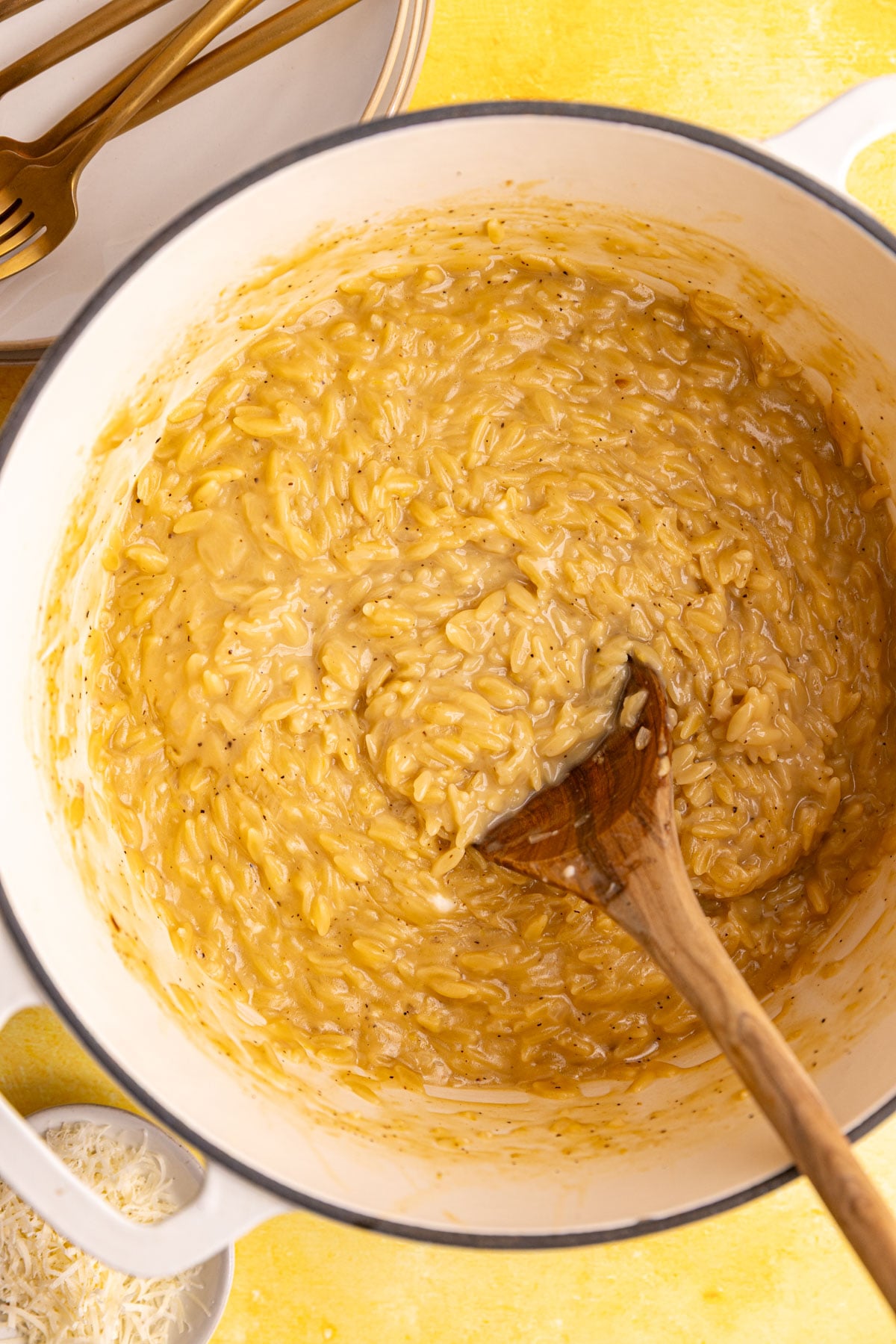A pot of freshly cooked Creamy Lemon Orzo, with a wooden spoon.