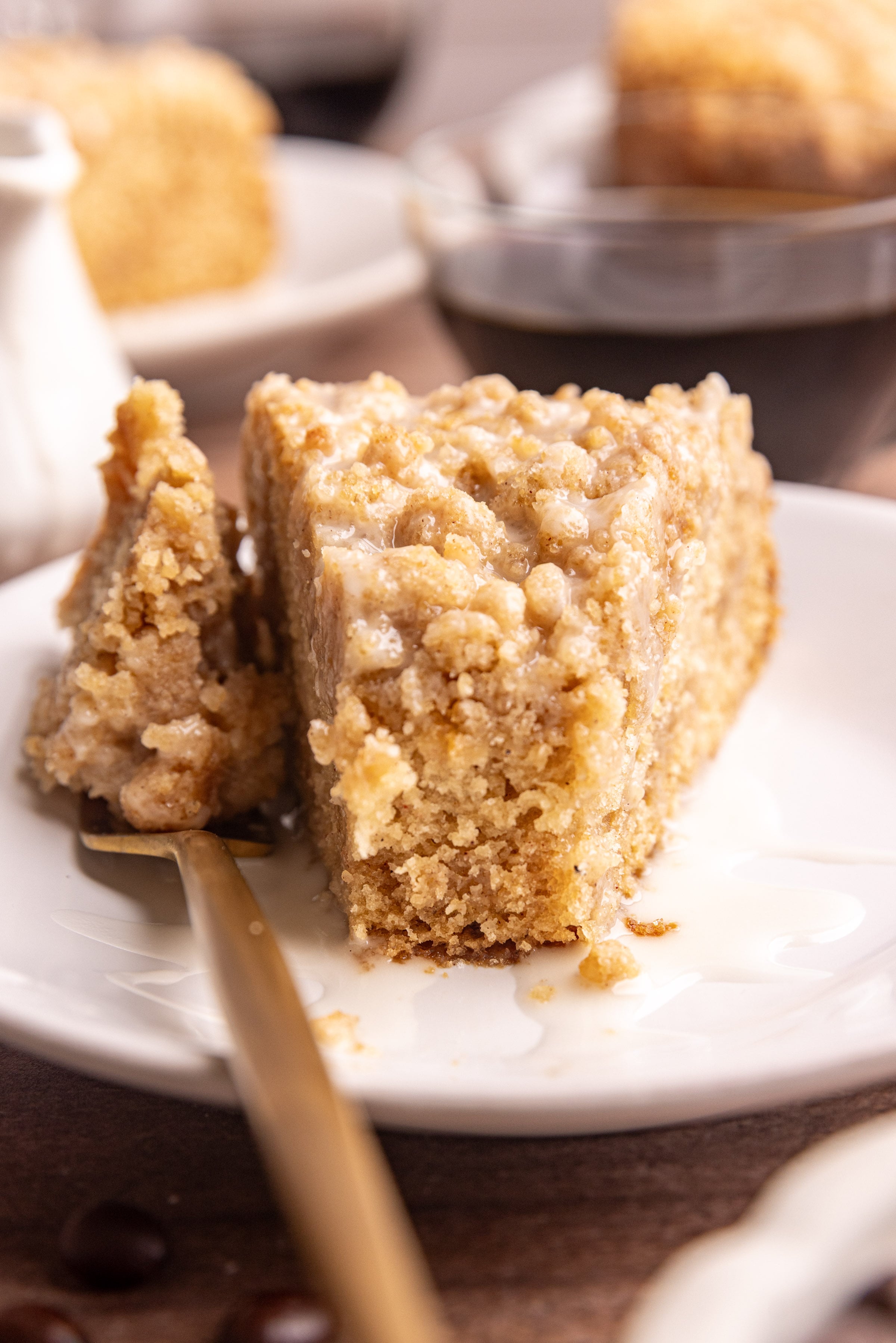 A slice of vegan cinnamon streusel coffee cake with fork taking a bite out.