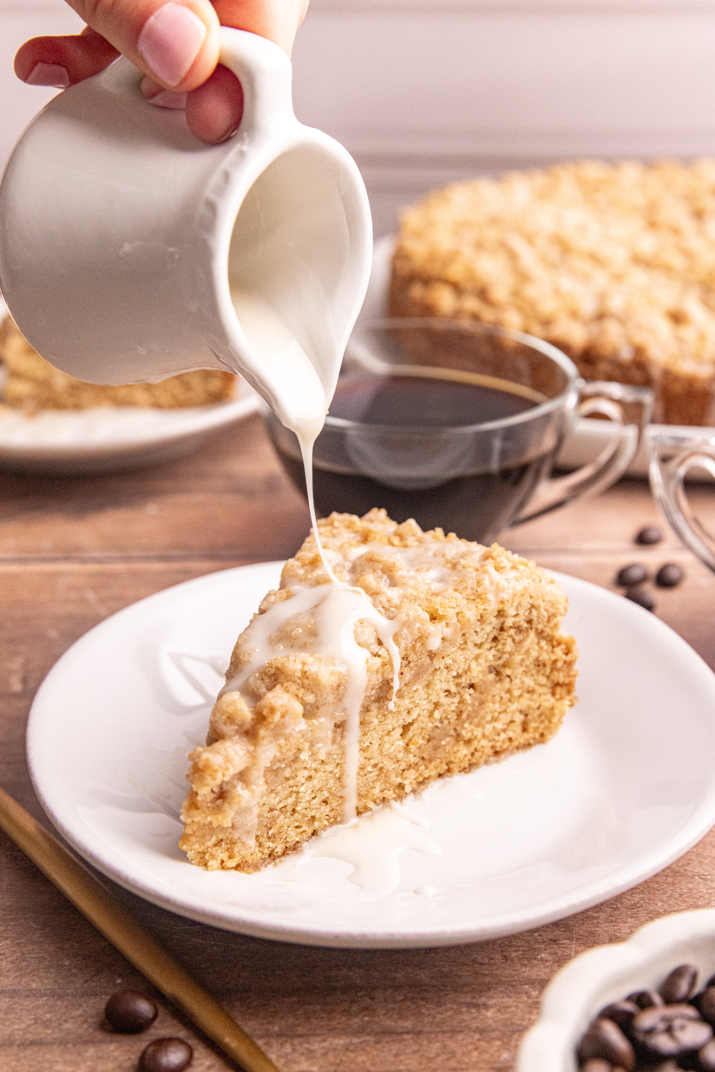 A slice of vegan cinnamon streusel coffee cake being glazed.