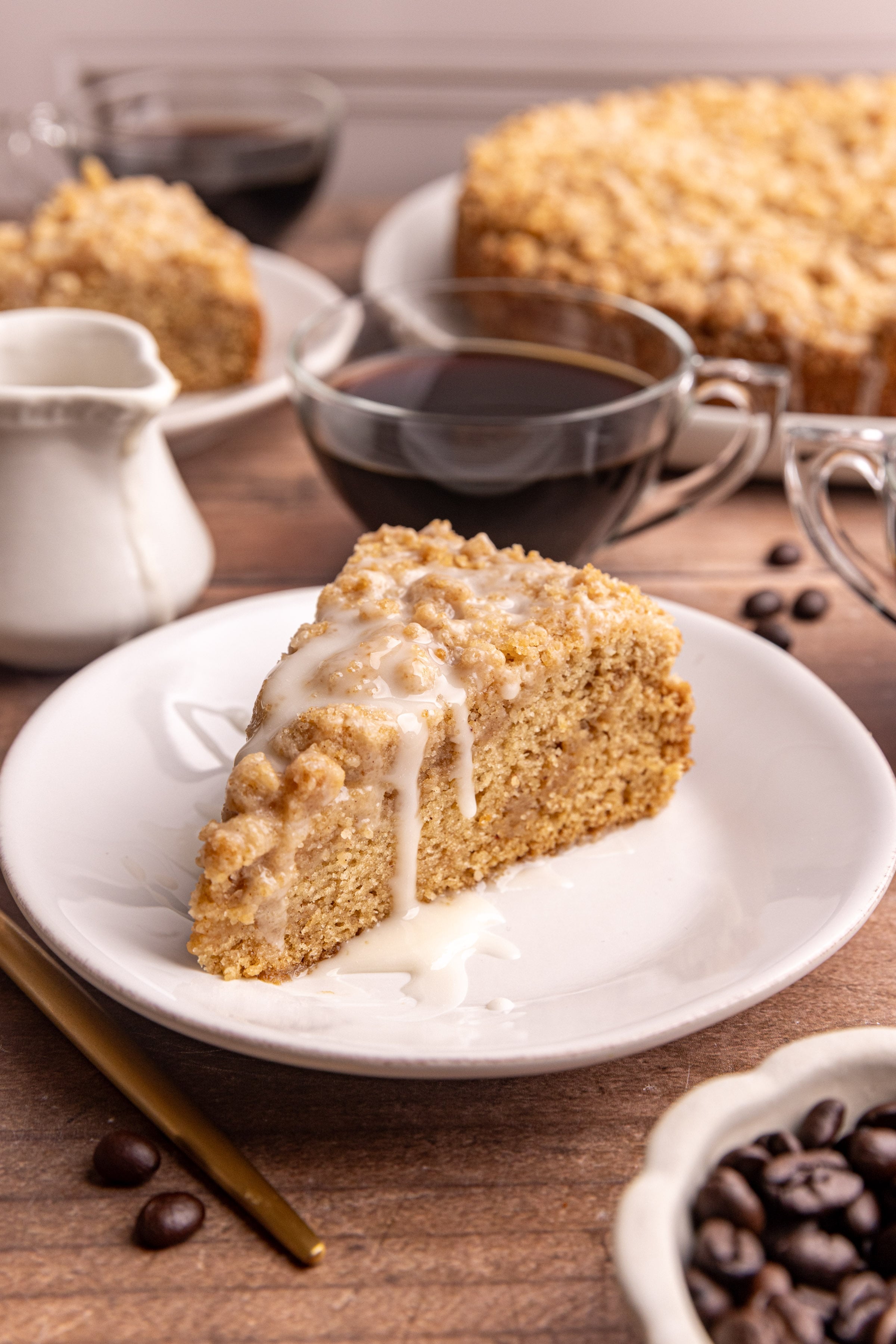 A slice of vegan cinnamon streusel coffee cake with a drizzle of glaze on top.