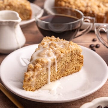 A slice of vegan cinnamon streusel coffee cake with a drizzle of glaze on top.