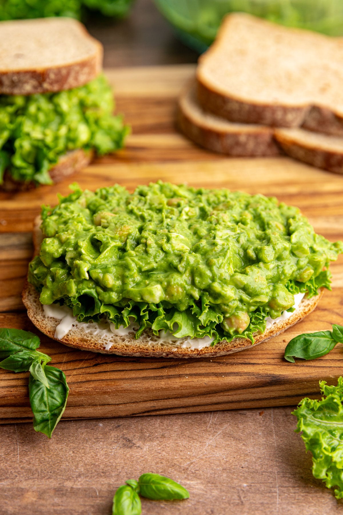 An open-faced green goddess chickpea salad sandwich, with lettuce and mayo.
