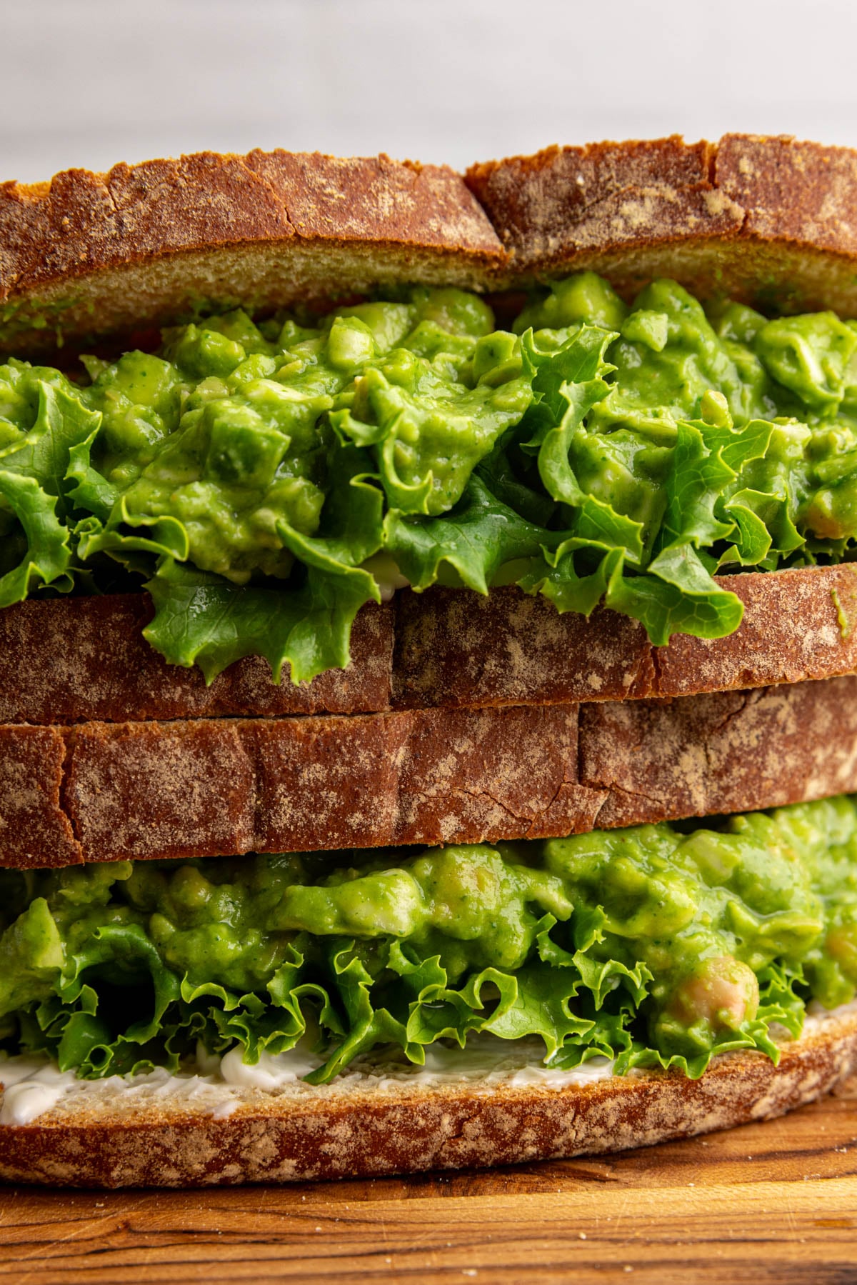 A double decker green goddess chickpea salad sandwich, with lettuce and mayo.