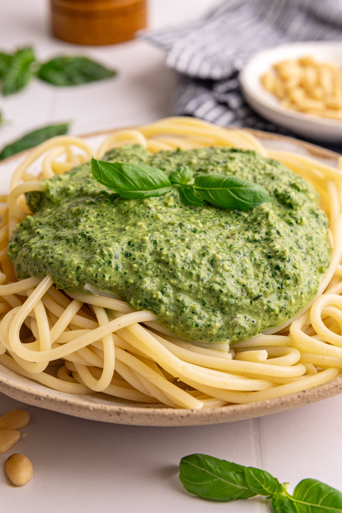 A bowl of spaghetti topped with Vegan oil free pesto, garnished with a basil leaf.