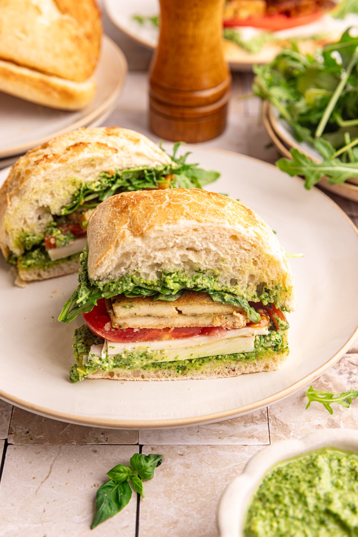 A vegan pesto sandwich, sliced in half to see the fluffy ciabatta, tofu, and pesto.