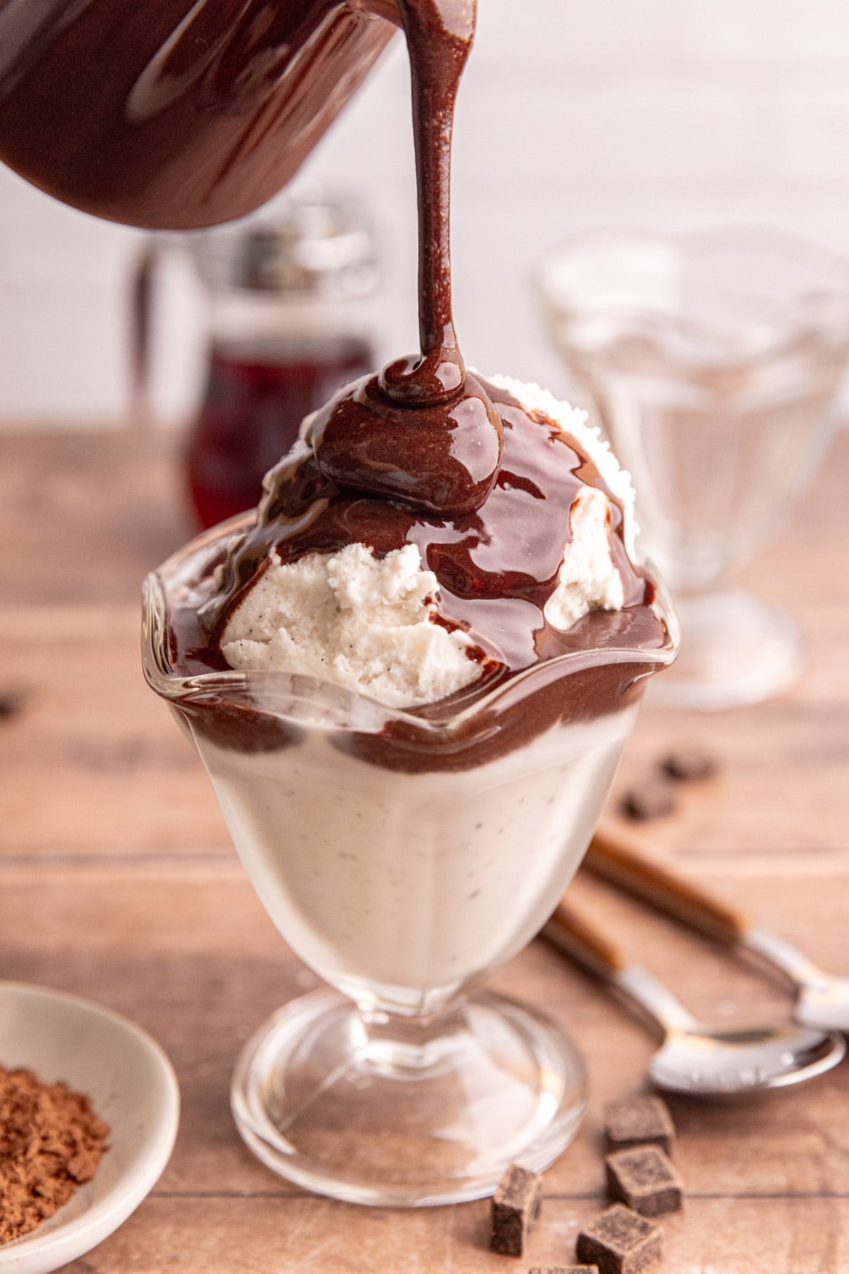 Maple chocolate syrup being poured onto a bowl of ice cream.