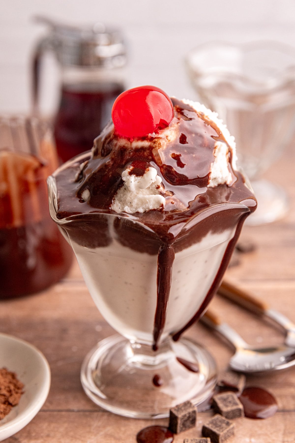 Maple chocolate syrup on a bowl of ice cream with a cherry on top.